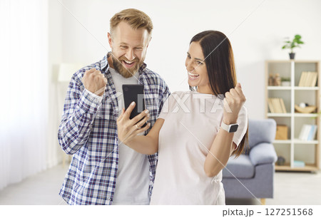 Man and woman get excited when they earn cash back, get discount or win money online 127251568