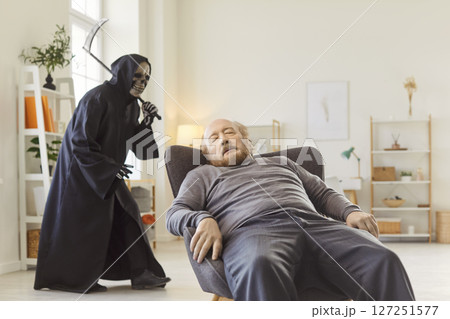 Unconscious senior man sitting at home with death holding scythe walking behind him Unconscious senior man sitting at home with death holding scythe walking behind him 127251577