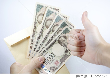5万円を手に持ち、右手でグッドサイン 127254377