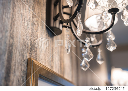 Elegant chandelier with intricate crystal pendants on a textured earthy wall, part of a sophisticated boutique hotel interior design. Elegant chandelier with intricate crystal pendants on a textured earthy wall, part of a sophisticated boutique hotel interior design. 127256945