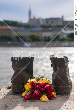 Rusted iron shoes on the Danube riverbank in Budapest, Hungary, with red and yellow flowers. Rusted iron shoes on the Danube riverbank in Budapest, Hungary, with red and yellow flowers. 127257038