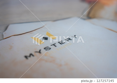 A close up view of the word Mystery in bold black letters with a yellow M logo above, set against a blurred background with warm tones. A close up view of the word Mystery in bold black letters with a yellow M logo above, set against a blurred background with warm tones. 127257145