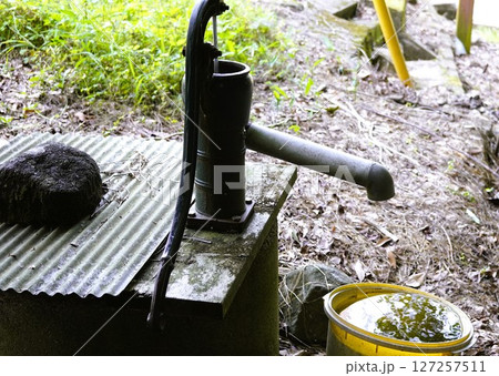 手押しポンプとバケツにたまった水 127257511