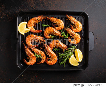 AI generated top view of succulent black tiger prawns grilled over charcoal, perfectly cooked with light smoky aroma. Seasoned with salt and black pepper, garnished with fresh rosemary and lemon. 127258990
