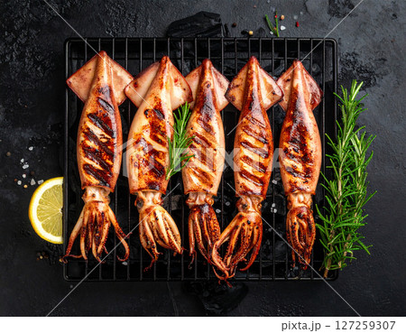 AI generated top view of fresh beka squid grilled over charcoal, perfectly cooked with tender texture and light smoky aroma. Seasoned with salt and black pepper, garnished with rosemary sprigs. 127259307