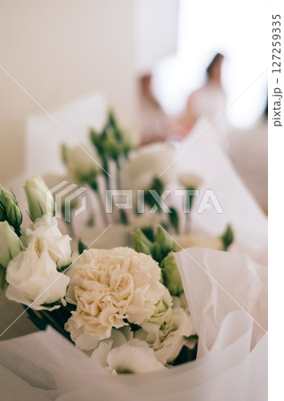 Close-up of white flower bouquet with soft background, wrapped in paper, romantic floral decor 127259335