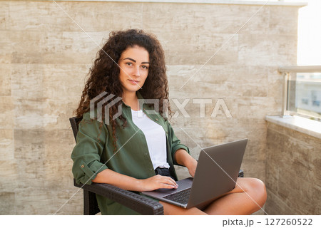 Portrait of a beautiful curly woman working on a laptop, looking at the camera, working on the Internet, online shopping, social networking, online learning, freelancer Portrait of a beautiful curly woman working on a laptop, looking at the camera, working on the Internet, online shopping, social networking, online learning, freelancer 127260522