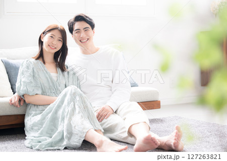 リビングでリラックスする若いカップル　カメラ目線　緑の前ボケあり 127263821