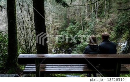 Contemplative couple on park bench appreciating a serene woodland view 127265194
