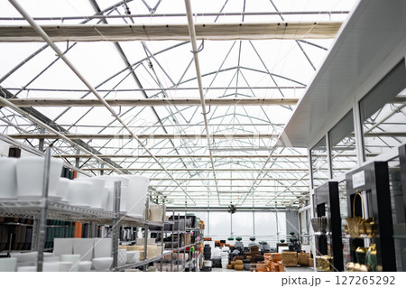 Inside a plant shop, flowerpots and supplies are displayed. The bright interior is spacious, perfect for various plants. Inside a plant shop, flowerpots and supplies are displayed. The bright interior is spacious, perfect for various plants. 127265292