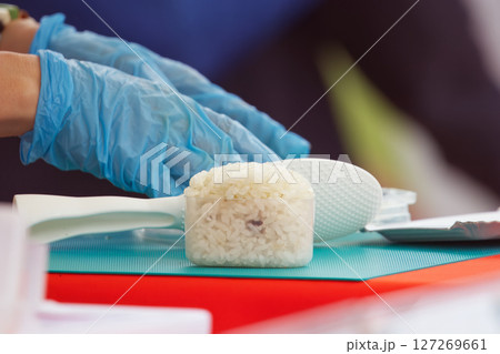 Gloved hands preparing rice with spatula, onigiri 127269661
