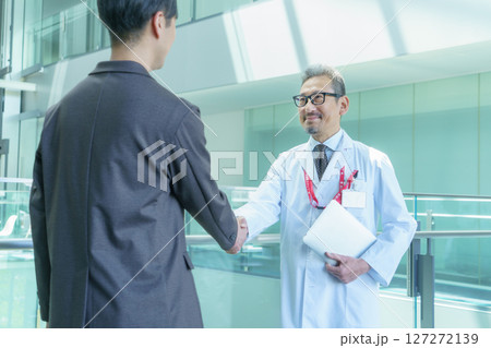 病院で握手する医師とスーツの男性　撮影協力:スカパー東京メディアセンター 127272139