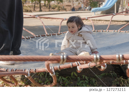 【相模原市立麻溝公園の子どもの広場のトランポリンでママと遊ぶ1歳児】 127273211