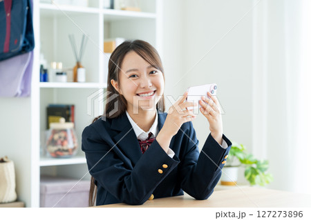 部屋でスマホを見る女子高生 127273896