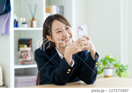 部屋でスマホを見る女子高生 127273897