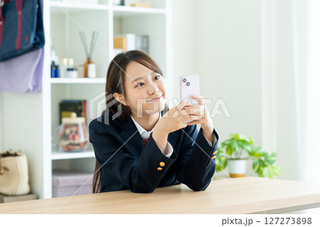 部屋でスマホを見る女子高生 127273898