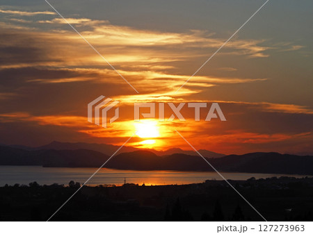 猪苗代湖対岸に沈む夕日。オレンジ色の太陽と雲に湖面の銀色の輝きが印象的で綺麗だ。 猪苗代湖対岸に沈む夕日。オレンジ色の太陽と雲に湖面の銀色の輝きが印象的で綺麗だ。 127273963