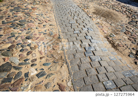 Two types of paving stones and cobblestones on a city road 127275964