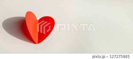 Banner with paper decoration in the shape of a red heart on a white background. Flat plan, top view, space for text on the right side 127275985