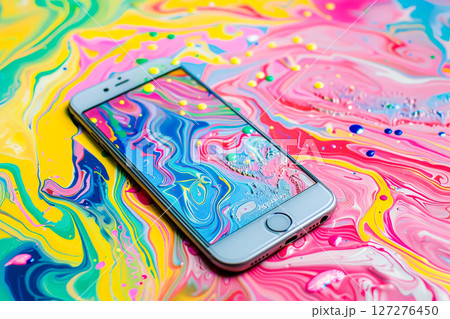 Phone is sitting on a colorful surface with a painting of a swirl pattern Phone is sitting on a colorful surface with a painting of a swirl pattern 127276450