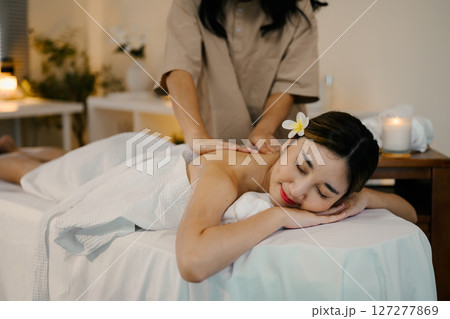 Relaxed woman lying on massage table while massage therapist massages her. Wellness concept Relaxed woman lying on massage table while massage therapist massages her. Wellness concept 127277869