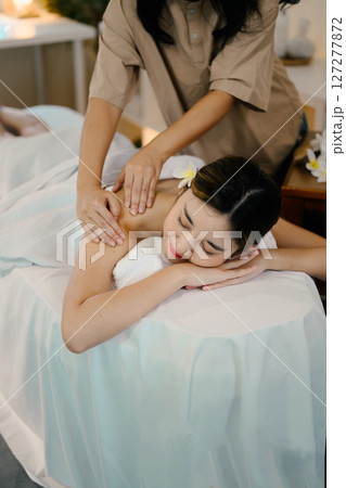 Relaxed woman lying on massage table while massage therapist massages her. Wellness concept Relaxed woman lying on massage table while massage therapist massages her. Wellness concept 127277872