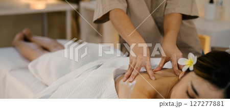 Closeup relaxed woman lying on massage table while massage therapist massages her Closeup relaxed woman lying on massage table while massage therapist massages her 127277881
