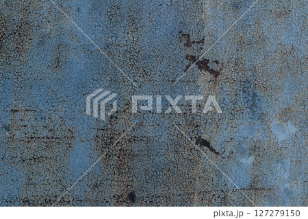 A blue and rusted wall with a lot of cracks and holes 127279150