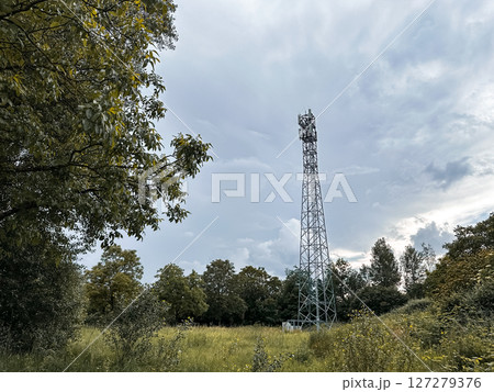 Tall tower is in the middle of a field with trees in the background 127279376