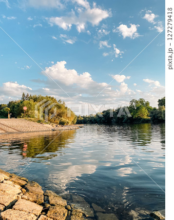 Calm body of water with a few trees in the background 127279418