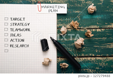 Black marker sits on a piece of paper with a marketing plan written on it 127279488