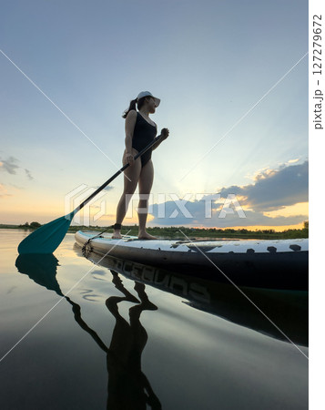 Paddleboarding at Sunset on a Tranquil Lake 127279672