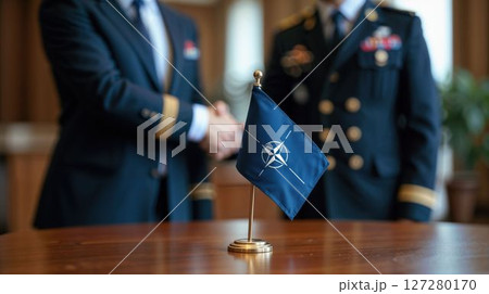 NATO flag with officers shaking hands in background 127280170
