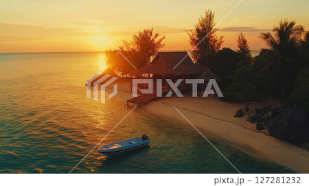 Breathtaking sunset over a tropical beach with a secluded wooden house and lush greenery 127281232