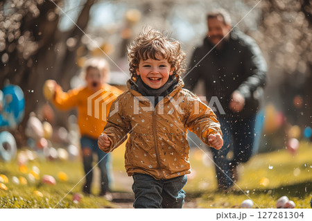 Young boy is running through a field with his father behind him 127281304