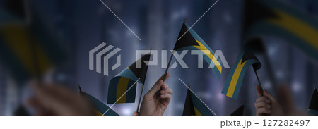 Bahamas flags in their hands on a blurred urban background 127282497