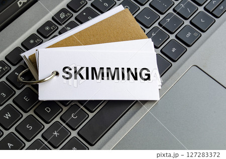 Skimming text on white notepad with laptop keyboard background. Hacker and scam activity concept Skimming text on white notepad with laptop keyboard background. Hacker and scam activity concept 127283372