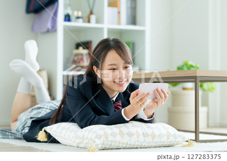 部屋でスマホを見る女子高生 127283375