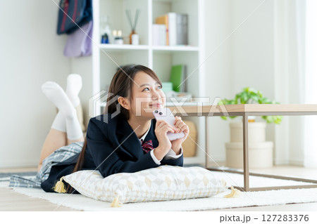 部屋でスマホを見る女子高生 127283376