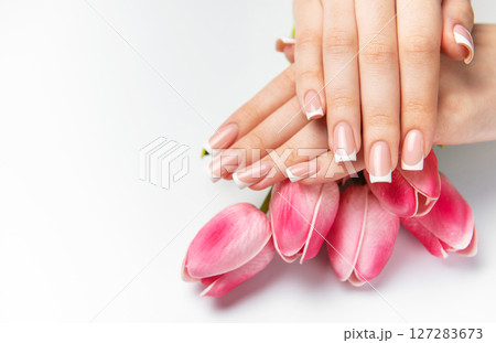 Woman showing french manicure and pink tulips on white background Woman showing french manicure and pink tulips on white background 127283673