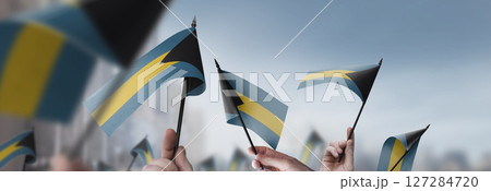 Bahamas flags in their hands on a blurred urban background 127284720