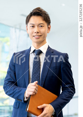 バインダーを持つ笑顔の男性ビジネスマン 127285236