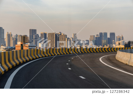 Curvy highway overpass with modern city background. 127286342