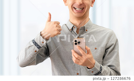 スマートフォンを持っていいね！のポーズをする男性 127286676