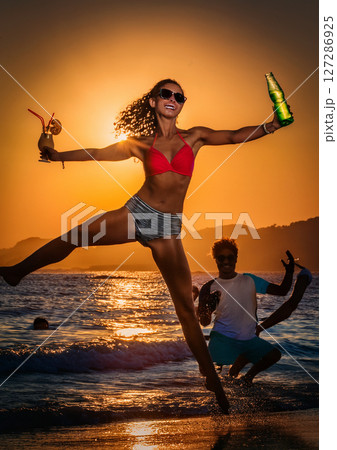 海辺でカクテルを持ってはしゃぐ女性 127286925