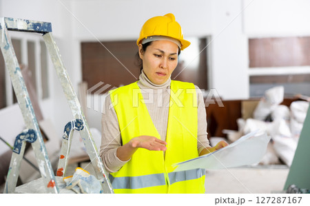 Woman worker checking documents during repair works indoors 127287167