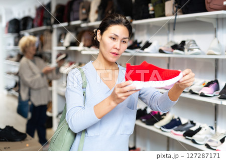woman selecting running shoes in shoeshop 127287171