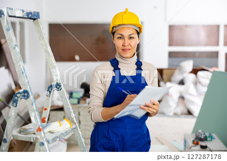 Woman foreman checks the completed construction work on drawing 127287178