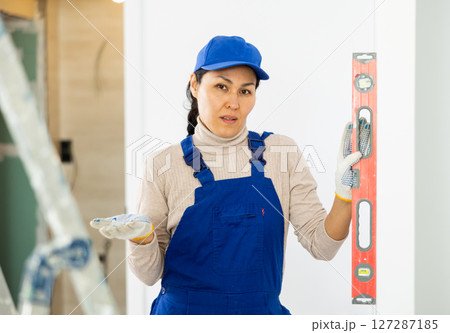 Female repairer setting level to wall 127287185