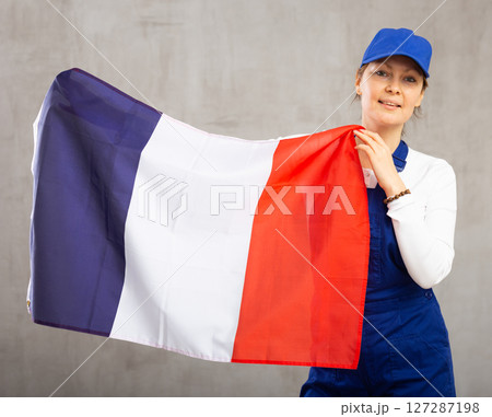 Cheerful female worker with wide grin on her face holding flag of france 127287198
